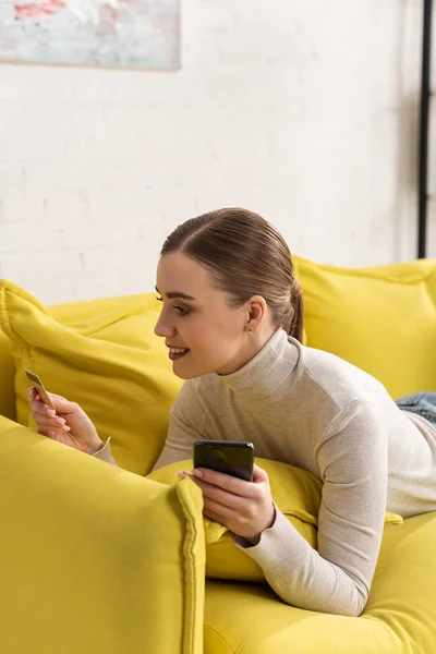 Smiling Attractive Girl Holding Credit Card Smartphone Couch — Stock Photo, Image