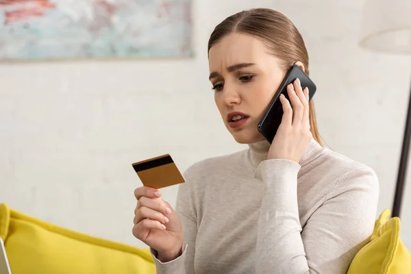 Preoccupata Giovane Donna Possesso Carta Credito Parlando Smartphone Casa — Foto Stock