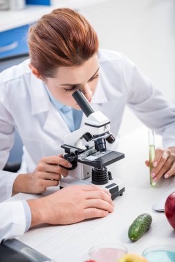 Laboratuvarda mikroskop kullanarak beyaz önlüklü moleküler beslenme uzmanı. 