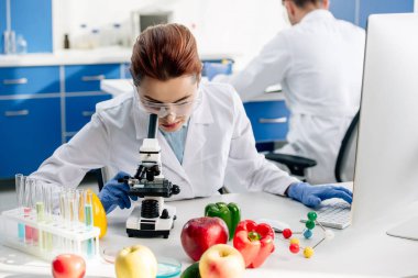 molecular nutritionist in white coat using microscope in lab  clipart