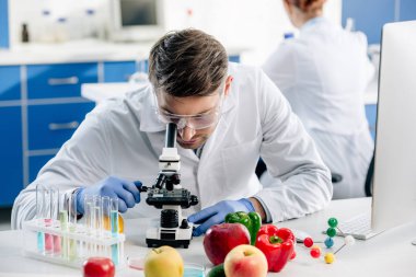 Laboratuvarda mikroskop kullanarak beyaz önlüklü moleküler beslenme uzmanı. 