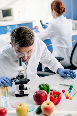 Laboratuvarda bilgisayar kullanarak beyaz önlüklü moleküler beslenme uzmanının seçici odağı 