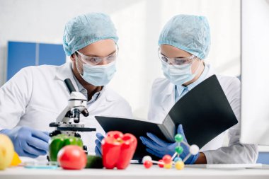 selective focus of molecular nutritionists looking at folder in lab  clipart