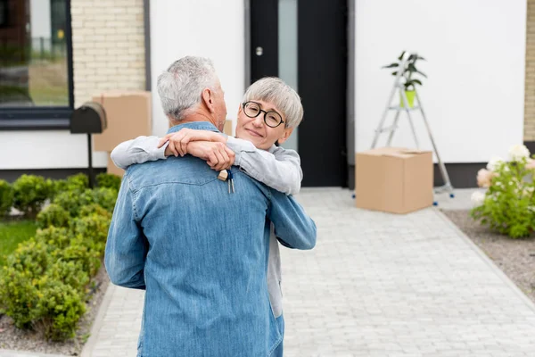 Smiling Woman Holding Keys New House Hugging Mature Man — Stock Photo, Image