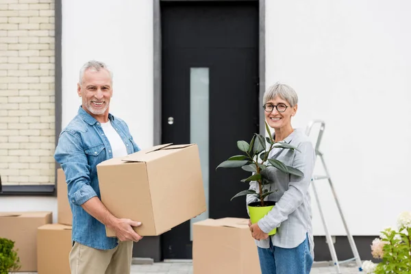 成熟的男人拿着盒子 微笑的女人拿着工厂靠近新房子 — 图库照片