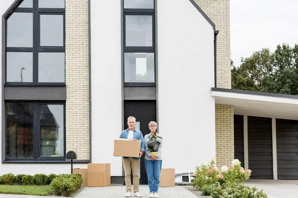 Mature Man Holding Box Woman Holding Plant New House — 스톡 사진