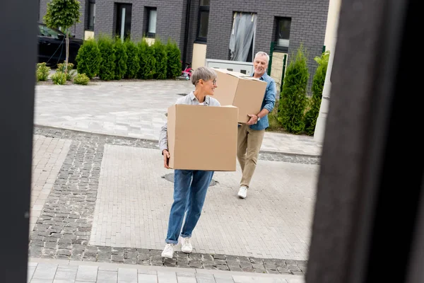 成熟的男人和微笑的女人带着箱子来到新房子 — 图库照片