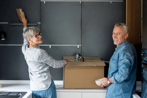 Mature Man Smiling Woman Unpacking Box New House — 스톡 사진