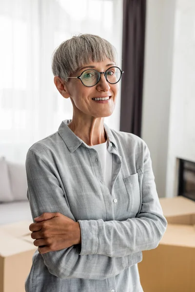 Donna Sorridente Con Braccia Incrociate Guardando Fotocamera Nella Nuova Casa — Foto Stock