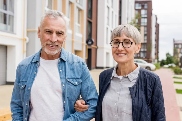 Mogen Man Och Leende Kvinna Tittar Kameran Nära Nya Byggnader — Stockfoto