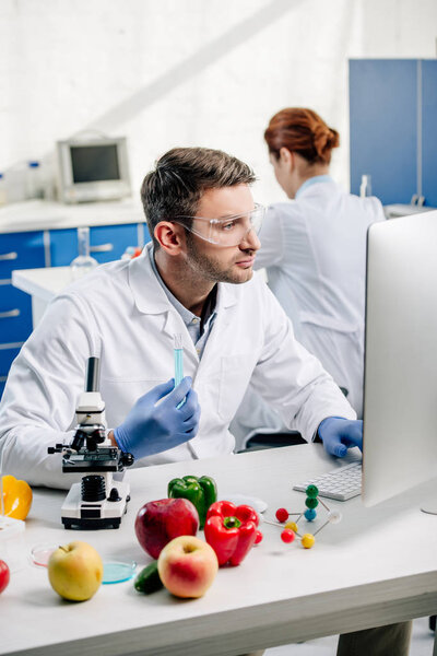molecular nutritionist holding test tube and using computer in lab 