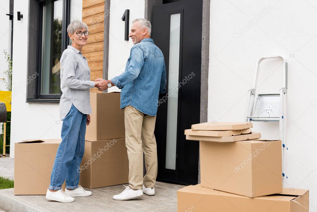 mature man looking at smiling woman and holding hands with her new house 