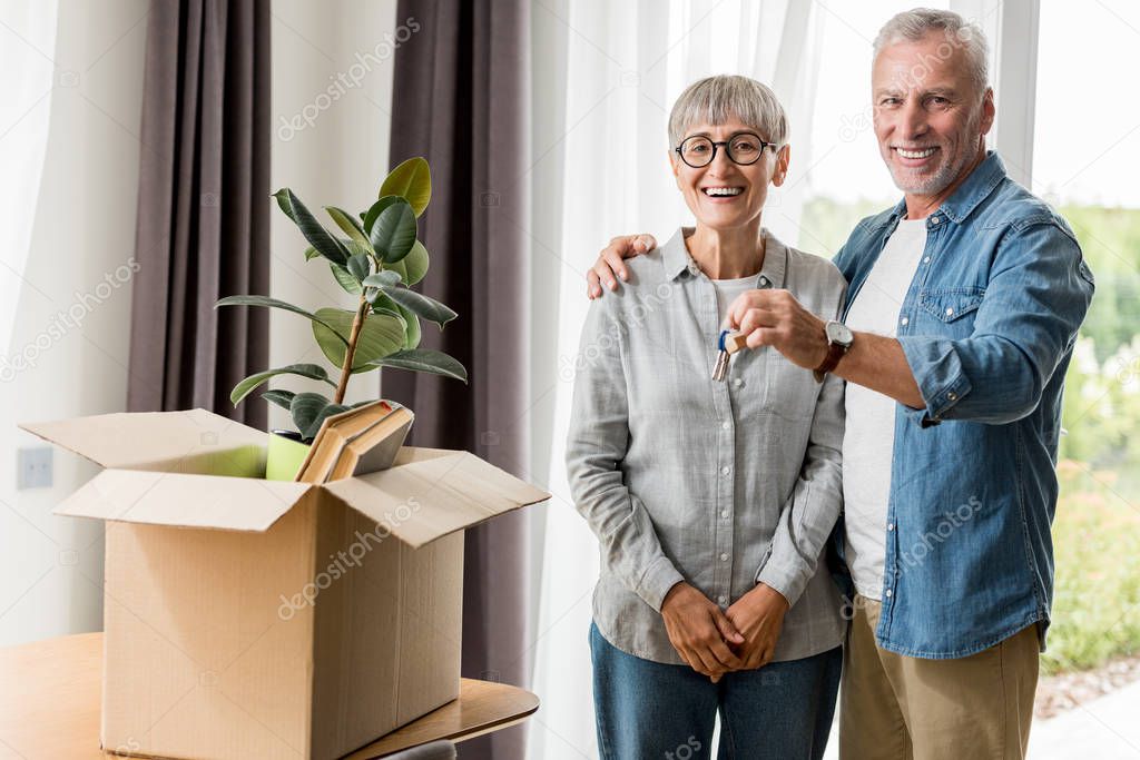 smiling man holding keys of new house and hugging woman 