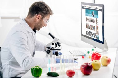 KYIV, UKRAINE - OCTOBER 4, 2019: side view of molecular nutritionist using computer with amazon website  clipart
