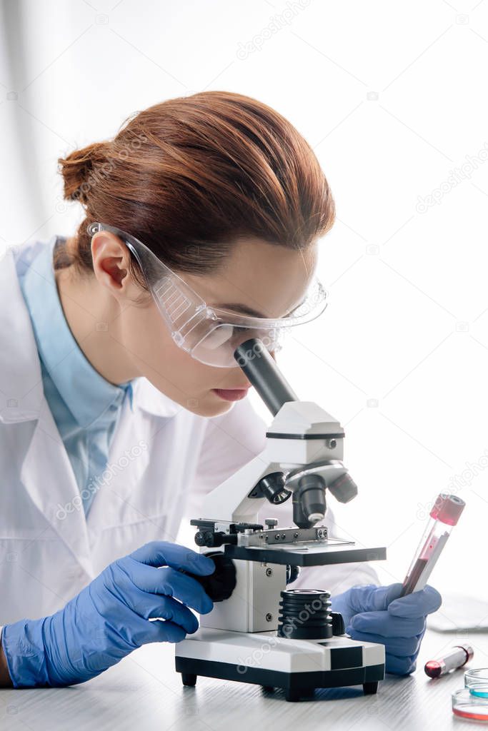 genetic consultant in white coat using microscope in lab 
