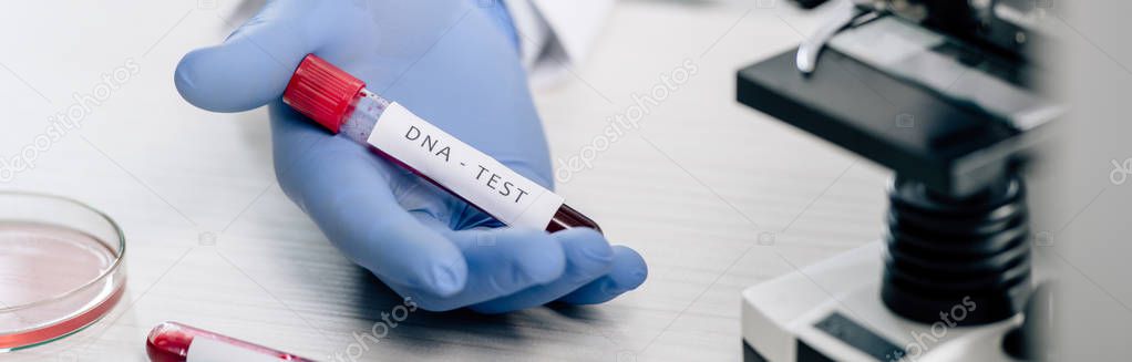 panoramic shot of genetic consultant holding test tube with dna test 