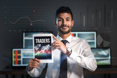 happy bi-racial man holding digital tablet with traders letters  clipart