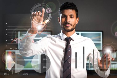 selective focus of handsome bi-racial trader pointing with fingers near computers on background  clipart