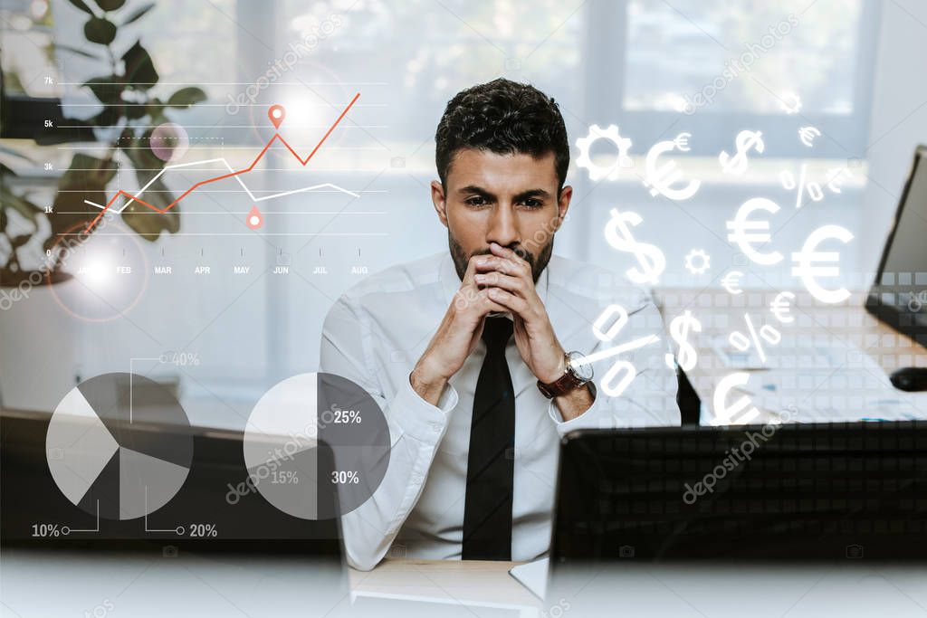 pensive bi-racial trader looking at computers near charts and graphs 