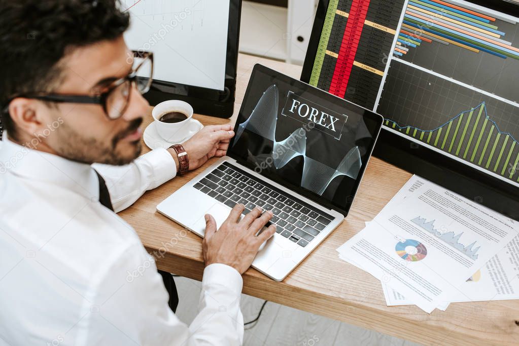 selective focus of bi-racial trader using laptop with forex letters 