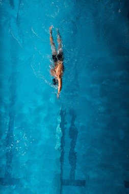Mavi suda yüzen sporcunun üst görüntüsü. 