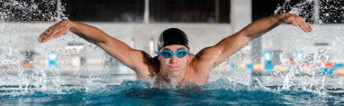 panoramic shot of handsome swimmer swimming butterfly stroke in swimming pool   clipart