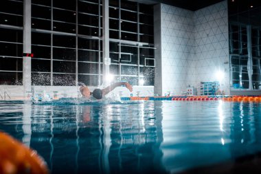 selective focus of sportsman swimming butterfly stroke in swimming pool  clipart