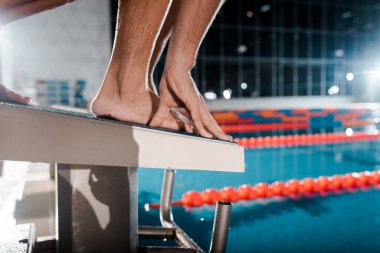 cropped view of athletic sportsman standing on diving block clipart