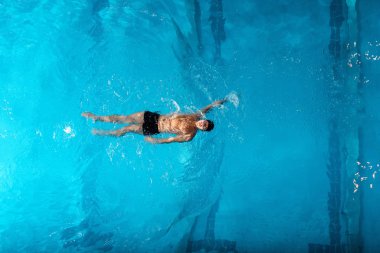 top view of sportsman in swimming trucks training in swimming pool  clipart