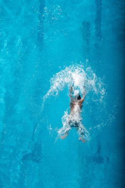 top view of swimmer diving into water in swimming pool  clipart