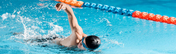 panoramic shot of handsome swimmer training in swimming pool 