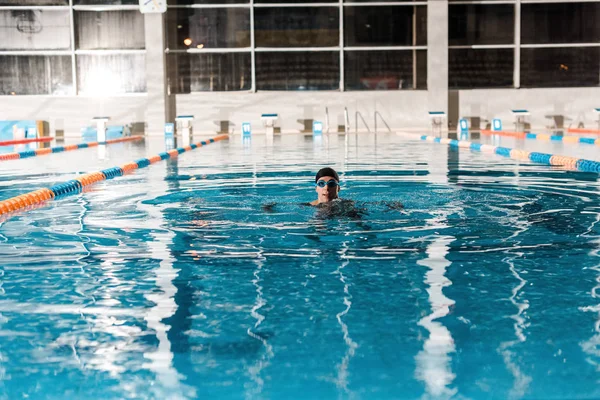 swimmer in goggles training in swimming pool