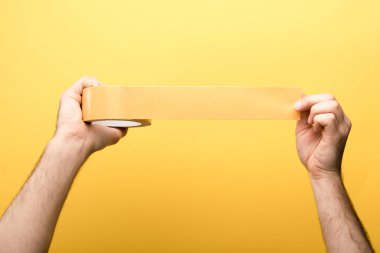Sarı arka planda yapışkan bant tutan bir adam görüntüsü 