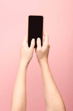 Akıllı telefonu pembe üzerine izole etmiş bir kadının görüntüsü. 