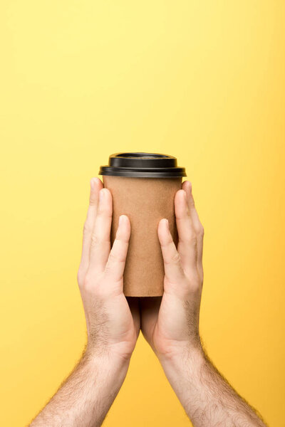 cropped view of man holding paper cup on yellow background 