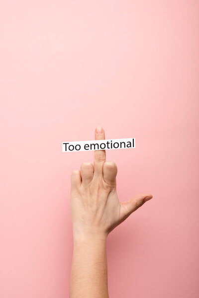 cropped view of woman showing middle finger and card with too emotional lettering on pink background 