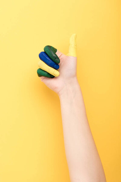 cropped view of woman with colorful fingers showing like on yellow background 