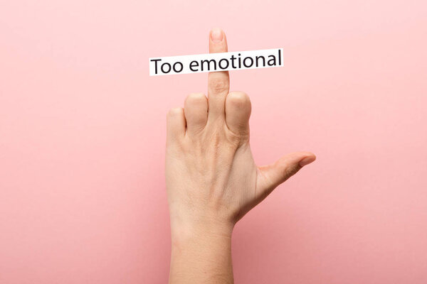 cropped view of woman showing middle finger and card with too emotional lettering on pink background 