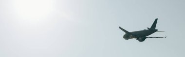 Panoramic shot of airplane in clear sky with sunlight clipart