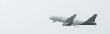 Airplane taking off in cloudy sky, panoramic shot clipart