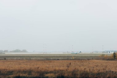 Arka planda bulutlu gökyüzü olan havaalanı pistinde uçak