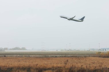 Airplane taking off in sky above foggy airfield clipart