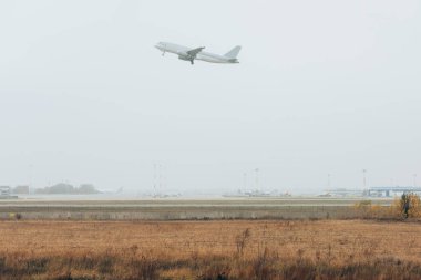 Airplane taking off above foggy airfield with runway clipart