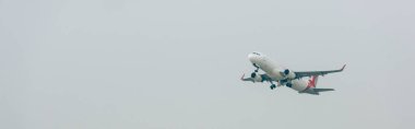 Panoramic shot of commercial plane in cloudy sky clipart