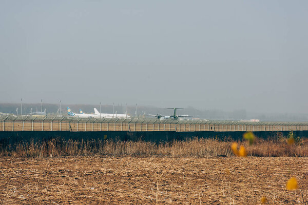 Коммерческие самолеты на аэродроме с облачным небом на заднем плане
