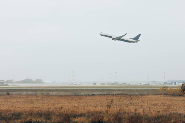 Самолёт приземляется на взлетно-посадочной полосе аэропорта с облачным небом на заднем плане
