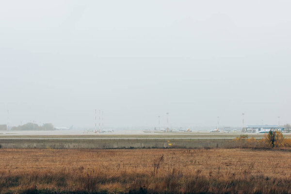 Взлетно-посадочная полоса аэропорта с травянистым полем и облачным небом
