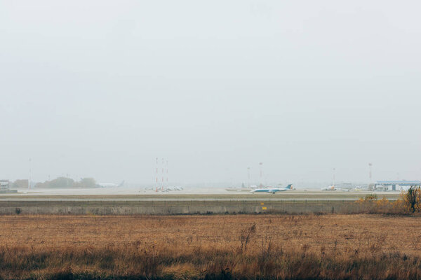 Airplane on airport runway with cloudy sky at background