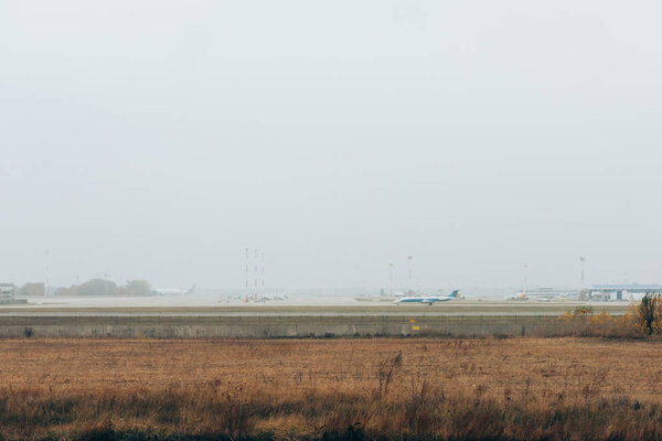 Самолет на взлетно-посадочной полосе аэропорта с облачным небом на фоне
