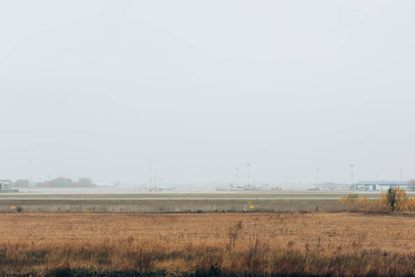 Planes on foggy airfield with cloudy sky